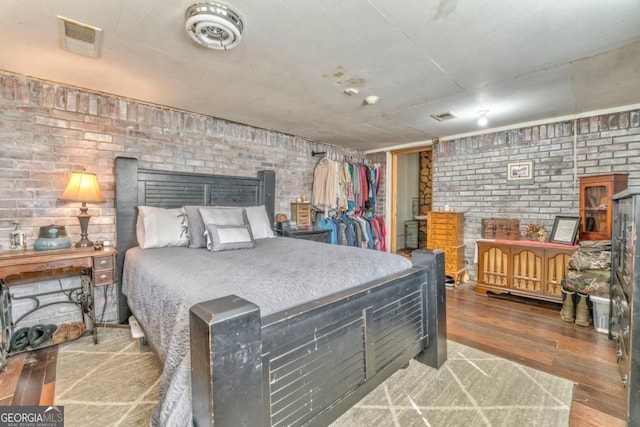 bedroom featuring wood-type flooring and brick wall