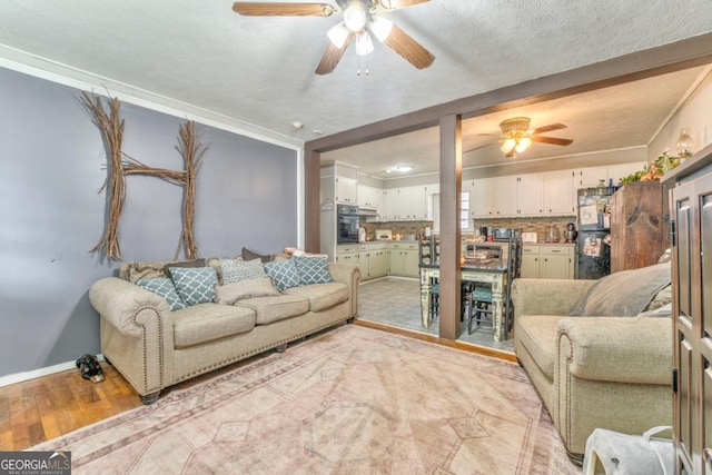 living room with crown molding, ceiling fan, a textured ceiling, and light wood-type flooring