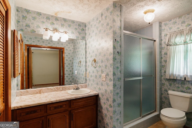 bathroom with vanity, a shower with shower door, toilet, and a textured ceiling