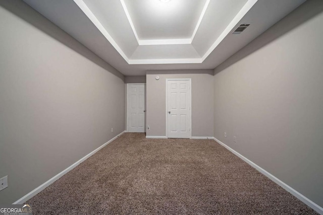 spare room featuring a raised ceiling and carpet