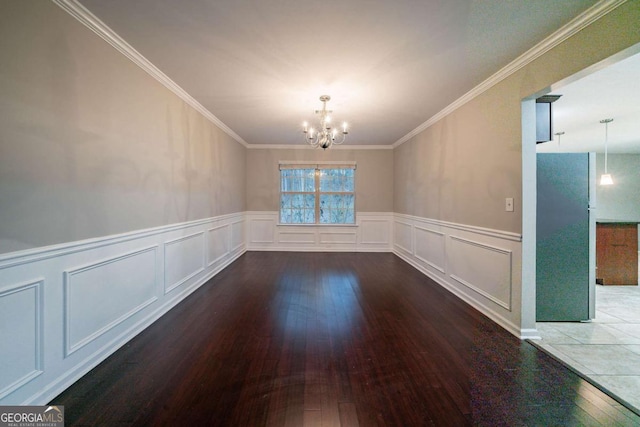 empty room with a notable chandelier, wood-type flooring, and ornamental molding