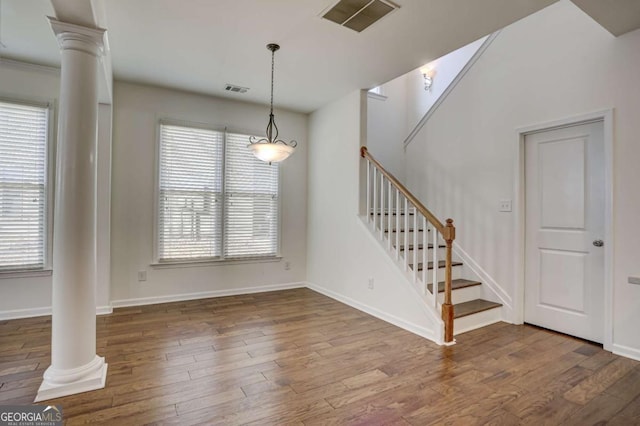 unfurnished dining area with decorative columns and dark hardwood / wood-style flooring