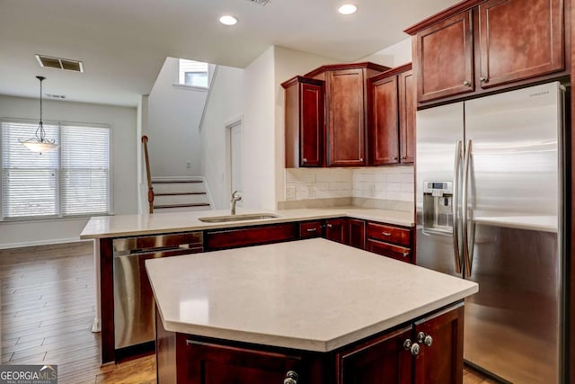 kitchen featuring sink, tasteful backsplash, hanging light fixtures, appliances with stainless steel finishes, and a kitchen island