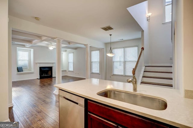 kitchen featuring sink, hanging light fixtures, dark hardwood / wood-style flooring, dishwasher, and decorative columns