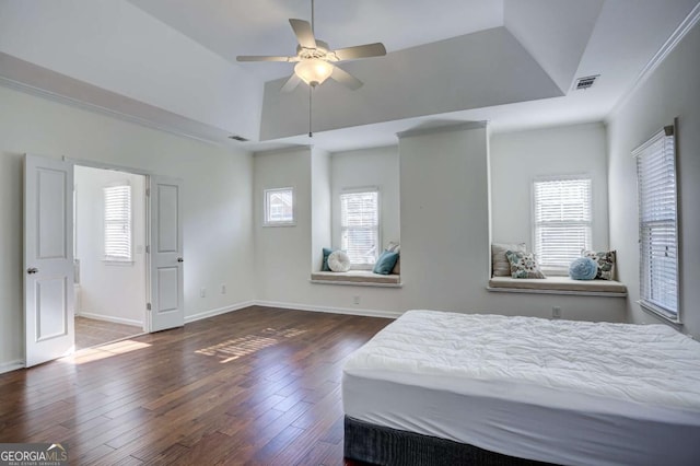 bedroom with dark wood-type flooring, ceiling fan, a tray ceiling, and crown molding