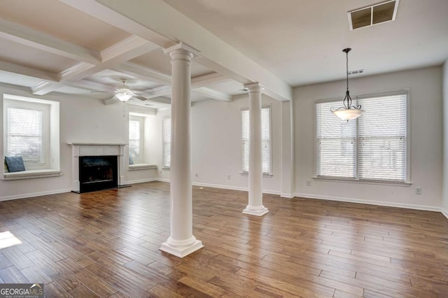 unfurnished living room featuring ceiling fan, dark hardwood / wood-style floors, decorative columns, and beam ceiling