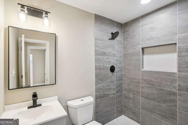 bathroom featuring tiled shower, vanity, and toilet