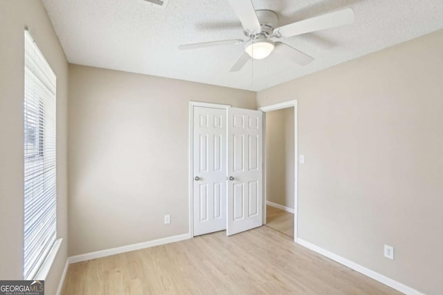 unfurnished bedroom featuring ceiling fan, light hardwood / wood-style flooring, a closet, and a textured ceiling