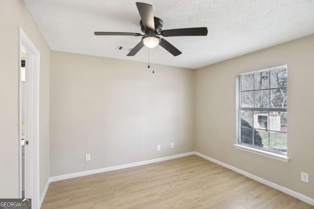 empty room with ceiling fan, light hardwood / wood-style floors, and a textured ceiling