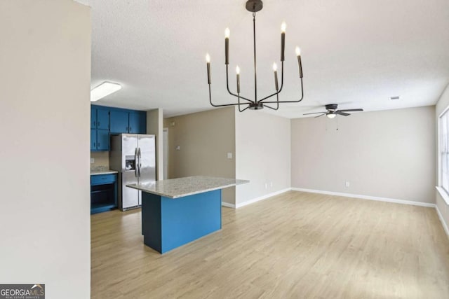 kitchen with pendant lighting, light hardwood / wood-style flooring, stainless steel refrigerator with ice dispenser, light stone counters, and blue cabinets