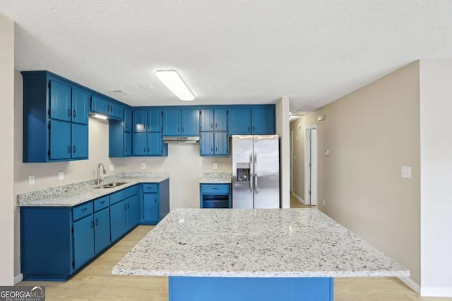 kitchen featuring sink, light hardwood / wood-style flooring, blue cabinetry, light stone counters, and stainless steel fridge with ice dispenser