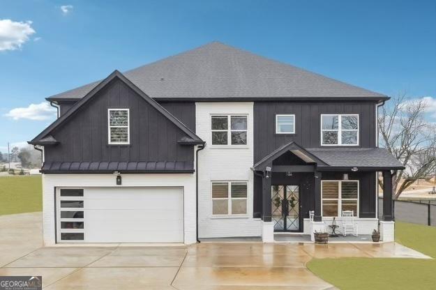 view of front of property featuring driveway, roof with shingles, board and batten siding, and an attached garage