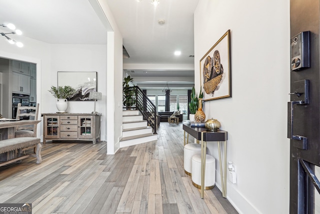interior space featuring stairs, light wood-style flooring, and baseboards