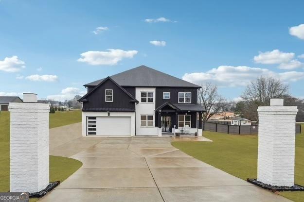 view of front of house featuring driveway, metal roof, a front yard, an attached garage, and fence
