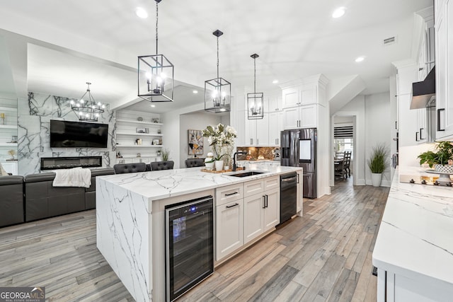 kitchen featuring under cabinet range hood, black appliances, a sink, white cabinetry, and wine cooler