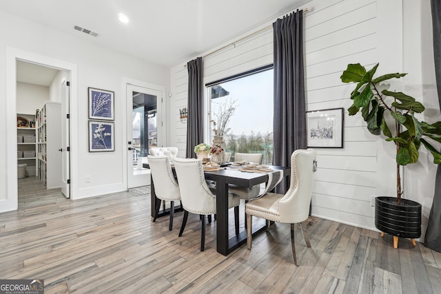 dining room with light wood finished floors, visible vents, and baseboards
