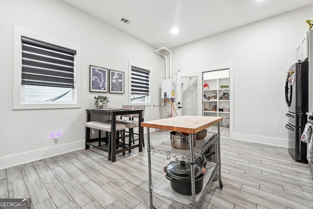 dining space featuring recessed lighting, tankless water heater, light wood-style flooring, baseboards, and visible vents