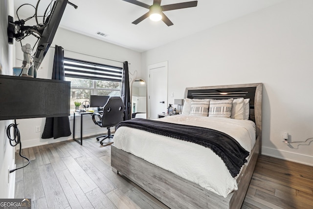 bedroom with wood finished floors, visible vents, ceiling fan, and baseboards