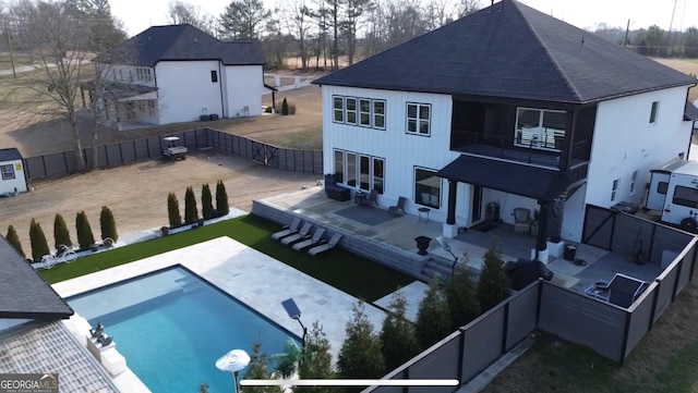 back of property featuring a balcony, a patio, a fenced in pool, a shingled roof, and a fenced backyard