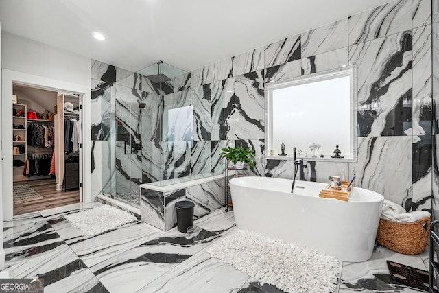 full bathroom featuring recessed lighting, marble finish floor, a freestanding tub, a walk in closet, and a marble finish shower