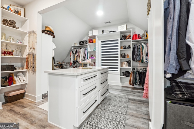 spacious closet featuring visible vents, light wood finished floors, and vaulted ceiling