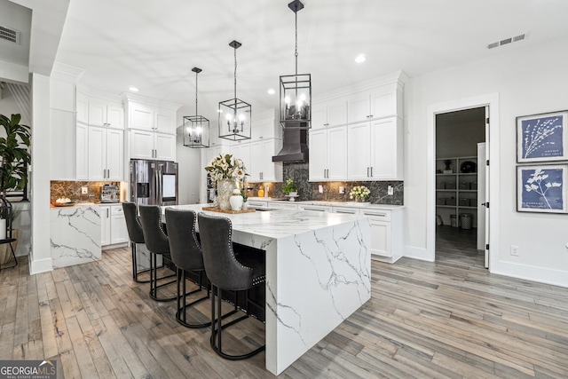 kitchen featuring decorative backsplash, recessed lighting, light wood finished floors, and wall chimney exhaust hood