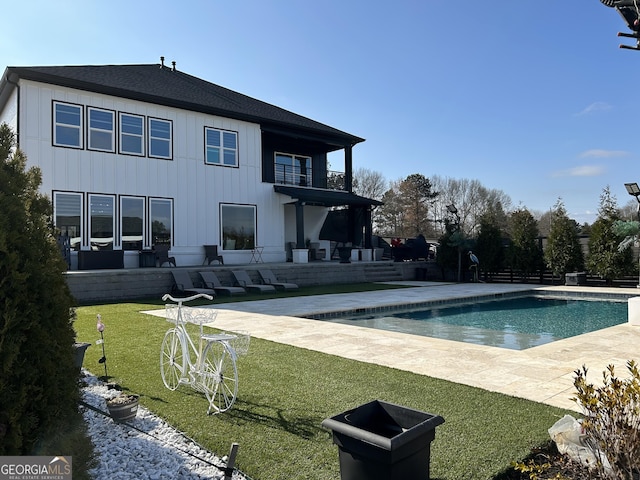 outdoor pool with a patio and a lawn