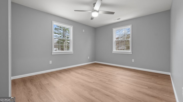 spare room featuring ceiling fan, light hardwood / wood-style floors, and a wealth of natural light