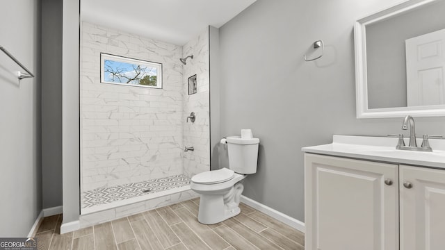 bathroom featuring tiled shower, vanity, and toilet