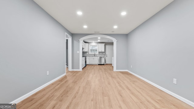 unfurnished living room with sink, ornate columns, and light wood-type flooring