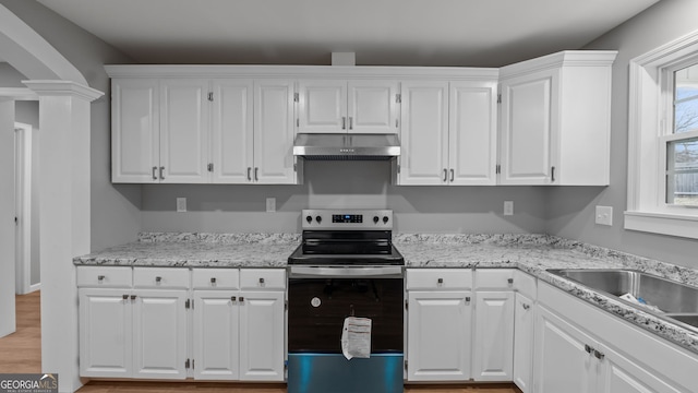 kitchen featuring sink, ornate columns, electric range oven, light wood-type flooring, and white cabinets