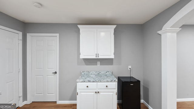 kitchen featuring ornate columns, light hardwood / wood-style floors, and white cabinets