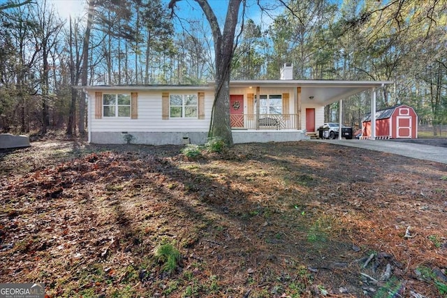 view of front of home with an attached carport, a shed, crawl space, driveway, and an outbuilding