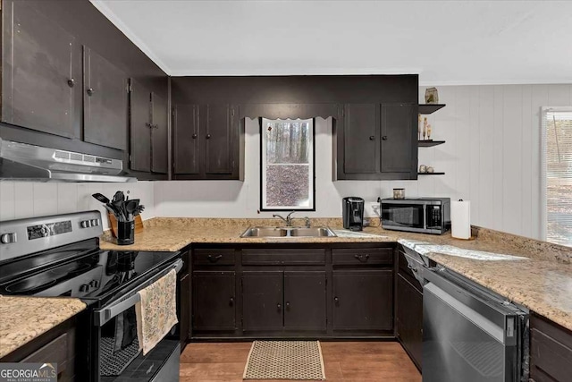 kitchen with appliances with stainless steel finishes, sink, dark brown cabinetry, light hardwood / wood-style floors, and light stone countertops