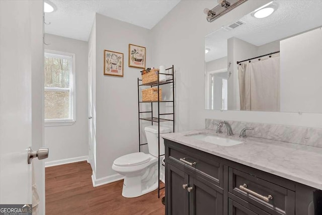 bathroom with vanity, toilet, hardwood / wood-style floors, and a textured ceiling