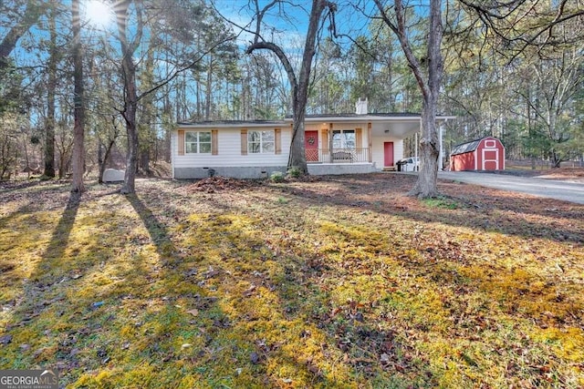 ranch-style house with a front lawn, a storage unit, and covered porch