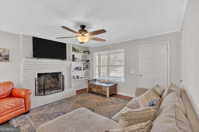 living room with crown molding, a brick fireplace, hardwood / wood-style flooring, and ceiling fan