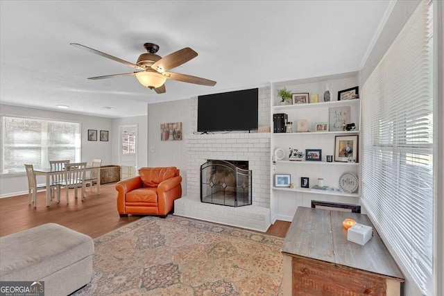 living room with ceiling fan, a fireplace, and light hardwood / wood-style floors