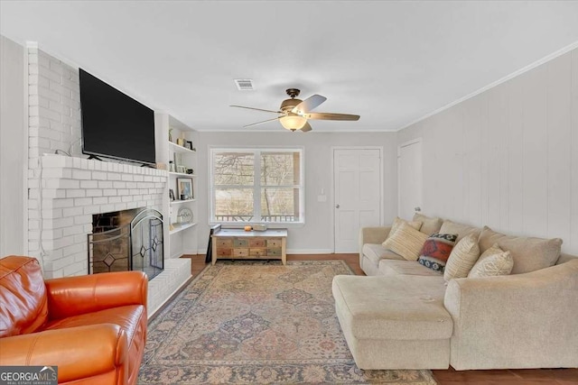 living room featuring hardwood / wood-style flooring, ceiling fan, ornamental molding, and a fireplace