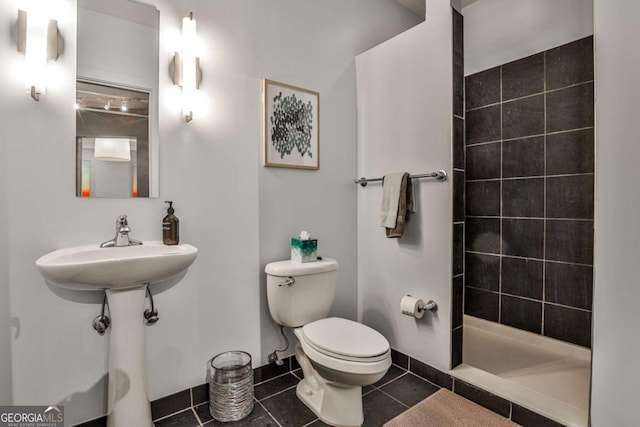 bathroom featuring tiled shower, toilet, and tile patterned flooring