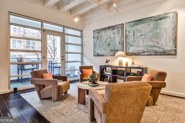 sitting room featuring beamed ceiling, track lighting, wood-type flooring, and a high ceiling