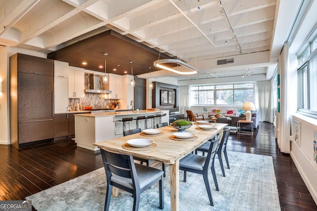 dining area with dark wood-type flooring, track lighting, and sink