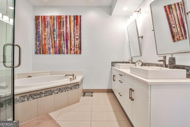 bathroom with tile patterned flooring, vanity, and a relaxing tiled tub