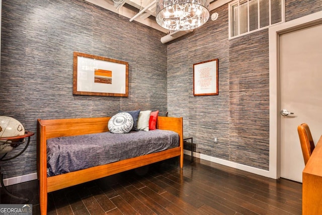 bedroom with dark wood-type flooring and an inviting chandelier