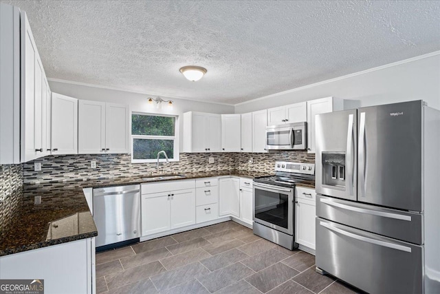 kitchen with tasteful backsplash, ornamental molding, white cabinets, stainless steel appliances, and a sink