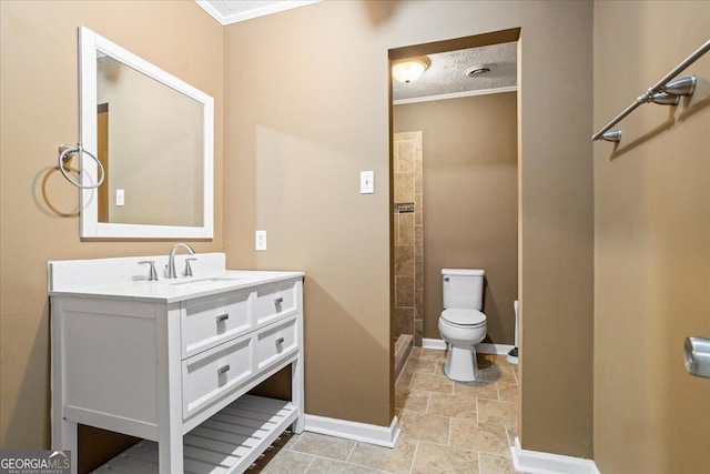 bathroom featuring vanity, baseboards, stone finish flooring, crown molding, and toilet