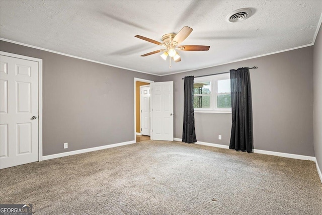 unfurnished bedroom featuring ceiling fan, ornamental molding, carpet floors, and a textured ceiling