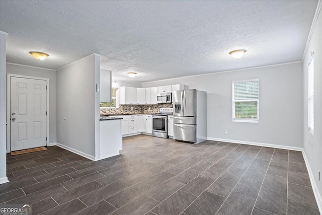 kitchen with ornamental molding, decorative backsplash, stainless steel appliances, white cabinets, and dark countertops