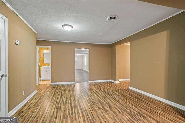 empty room featuring hardwood / wood-style flooring, ornamental molding, and a textured ceiling