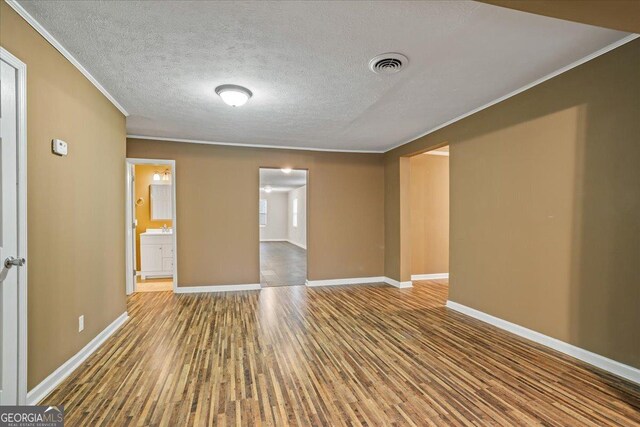 unfurnished room featuring visible vents, crown molding, baseboards, and wood finished floors